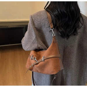 Détail du sac à bandoulière marron en suédine avec boucle métallique et sangle décorative