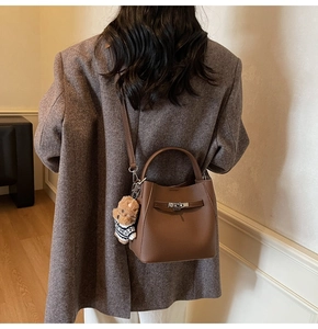 Detailed shot of brown pebble leather bucket bag with silver clasp and cute bear charm