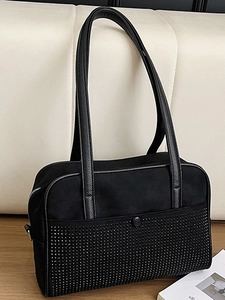 Grand sac cabas noir en daim avec rivets argentés et poignées en cuir sur un canapé