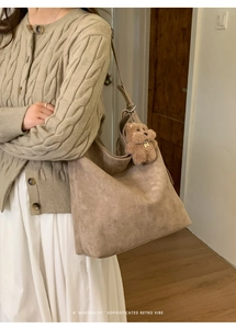 Détail d'un grand sac cabas en daim avec un charm d'ours en peluche brun en intérieur