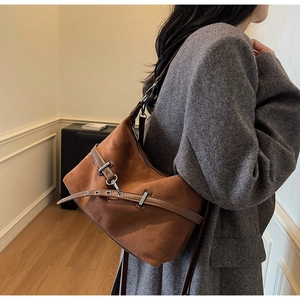 Gros plan du sac porté épaule en daim marron avec boucle en métal et texture vintage