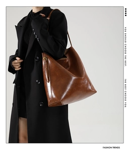 Detail einer braunen Leder-Shopper-Tasche mit glänzender Textur und Metallbeschlägen