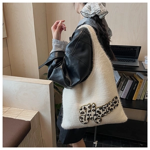 Detail of plush cream tote bag featuring leopard print M patch and soft knitted texture