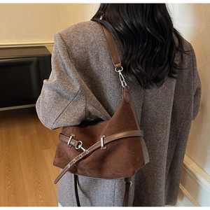 Détail du sac bandoulière en daim marron foncé avec boucle argentée et couture latérale