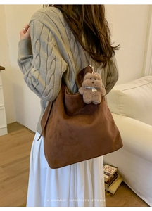 Sac cabas en daim marron avec pendentif ours en peluche dans un décor intérieur