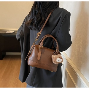 Retro coffee brown Boston bag with fluffy bear charm shown in a cozy lifestyle setting