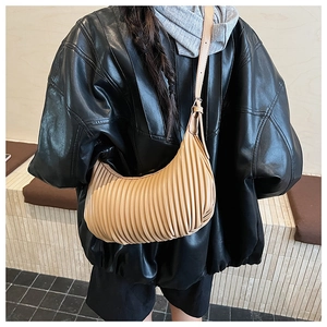 Detailed view of beige pleated crescent shoulder bag shown on a model in profile