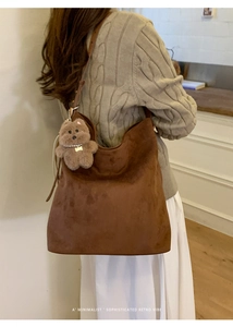 Détail du sac hobo en daim marron avec un charme d'ours en peluche et un style rétro