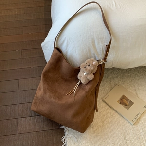 Détail du sac hobo en daim marron foncé avec breloque ours et large bandoulière