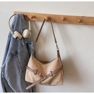 Détails de texture du sac en daim beige avec bandoulière en cuir brun et boucles en métal