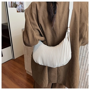 Detailed view of cream pleated crescent bag with adjustable leather strap and metal buckle
