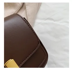 Détail des coutures précises sur le sac en cuir marron foncé avec boucle dorée élégante
