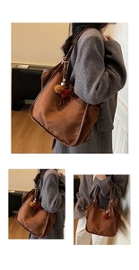 Détails d'un grand sac cabas en suédine marron avec un porte-clés pompon en peluche bicolore