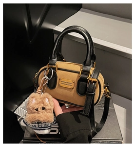 Dettaglio della borsa Boston in camoscio kaki con finiture in pelle e ciondolo a cucciolo
