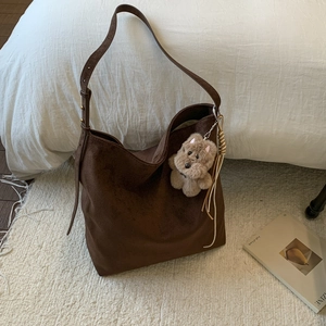 Détail d'un sac hobo en daim marron avec boucle ajustable et breloque chien en peluche