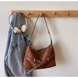 Détail d'un sac à bandoulière en daim marron avec sangle décorative en cuir et métal