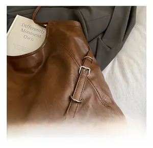 Close-up of brown faux leather tote bag showing fine stitching and silver metal buckle detail
