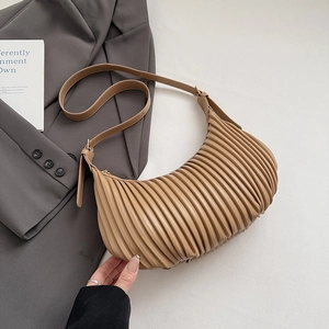 Close-up of vertical pleated texture on a khaki crescent shoulder bag with strap