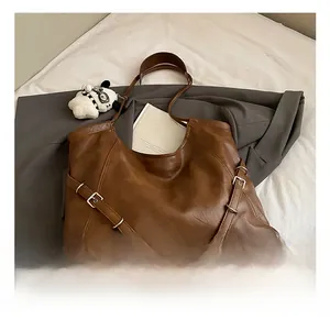 Detail view of vintage brown tote bag with silver buckle accents and matte faux leather texture
