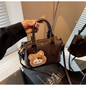 Detail view of brown vintage Boston bag with plush bear charm and golden hardware