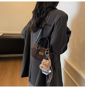 Dettaglio borsa Boston in camoscio marrone con ciondolo in peluche e accessori color oro