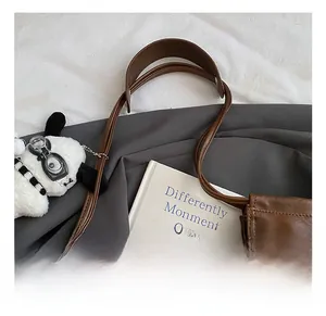 Detail view of smooth leather handle and cute white puppy plush charm on dark brown tote