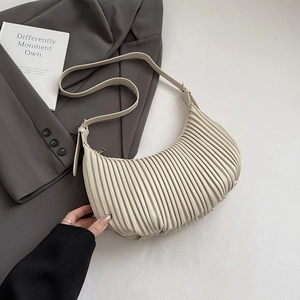 Detail of cream pleated crescent underarm bag on grey blazer for a modern aesthetic