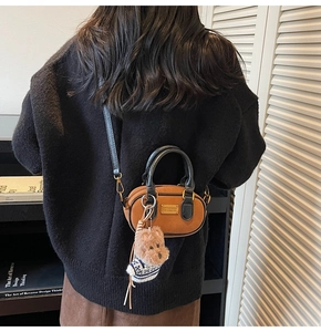 Dettaglio borsa vintage in pelle scamosciata marrone con ciondolo a cane e targa in metallo