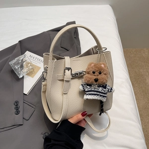 Detail of off-white lychee leather bucket bag with cute dog pendant and thin strap