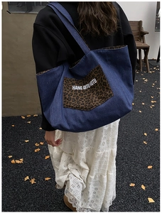 Macro view of blue denim tote bag featuring a leopard print pocket with white lettering