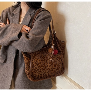 Détail du sac cabas léopard avec bordure en cuir marron et pendentif à pompon