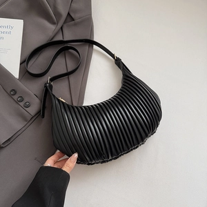Detail of black pleated crescent handbag on grey fabric with adjustable leather strap