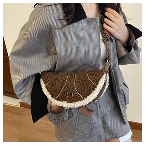 Detail van pluchen bruine crossbodytas in croissantvorm met schattig borduursel