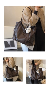 Macro view of a large dark brown tote bag with smooth texture and side buckle detail