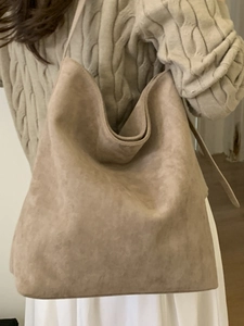 Grand sac cabas en daim abricot porté à l'épaule pour un style vintage chic