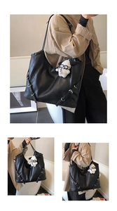 Detail of black tote bag featuring silver buckle straps and white plush sheep pendant