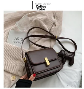 Détail du sac carré en cuir marron café avec fermoir doré et charm chien