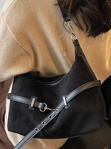 Sac bandoulière minimaliste noir mat avec garnitures argentées porté par un modèle