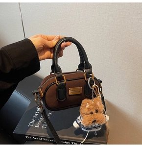 Dettaglio borsa opaca marrone caffè con manico in pelle e ciondolo a forma di cucciolo