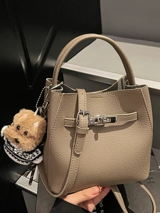 Minimalist pebbled leather bucket bag in taupe with puppy charm and crossbody strap