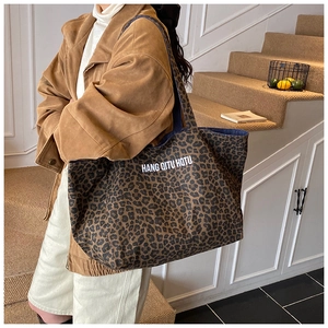 Detailed view of large leopard print canvas tote bag with white HQTU lettering on side