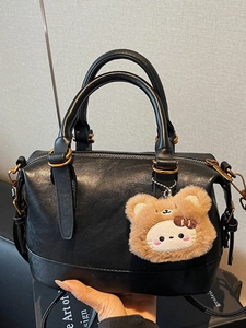 Retro black leather handbag with dual handles and a brown plush bear charm detail