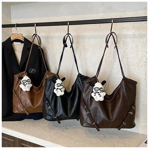 Three large capacity leather tote bags in brown and black with plush dog charms on a rack