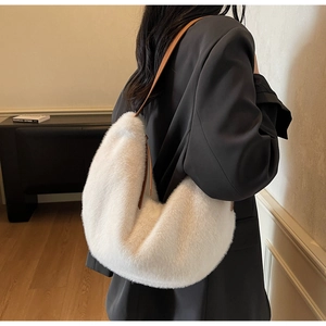 Detail of white faux fur shoulder bag with premium leather strap worn by a model