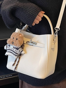 Elegant white lychee leather bucket bag with metal rotary clasp and cute bear charm pendant