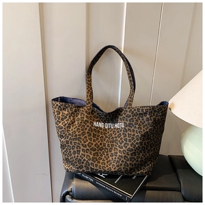 Detailed close-up of leopard print canvas tote bag with bold text on artistic book
