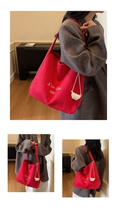 Vue détaillée du sac cabas en toile rouge avec lettrage blanc et petit pendentif