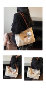 Detail view of large cream tote bag with brown woven straps and cloud plush charm