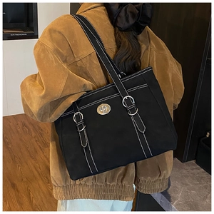 Détail du sac cabas noir avec surpiqûres blanches et boucle métallique argentée