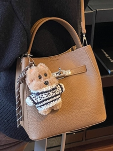 Minimalist brown pebbled leather bucket bag with silver lock and bear charm accessory